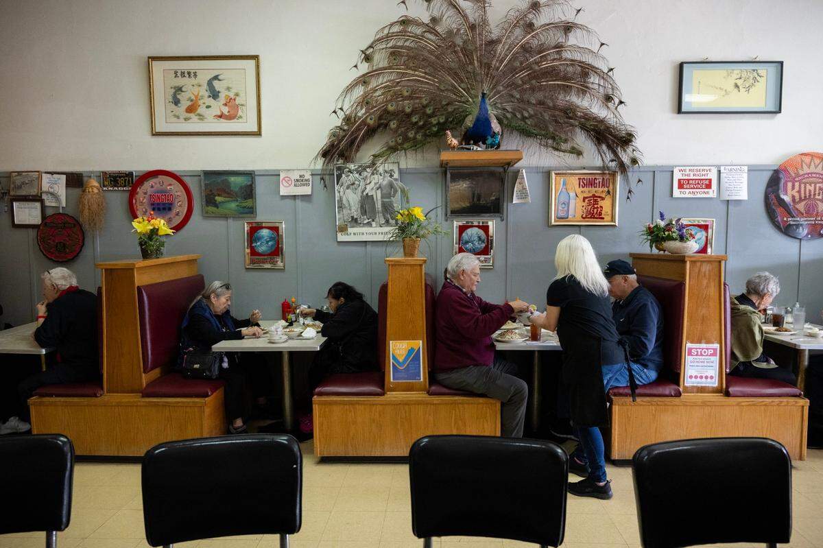 Customers eat in booths, decorated with gifts from customers, including a stuffed peacock, at the Chicago Cafe in Woodland last month.