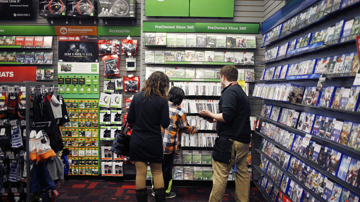 An employee assists customers shopping for Microsoft Xbox 360 video games inside a GameStop Corp. store in Louisville, Ky., on March 15, 2018. In June 2018, the company confirmed reports that its in talks with third parties for a potential buyout.