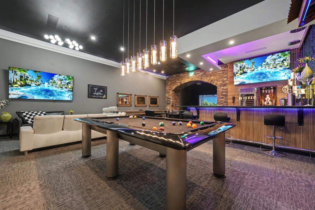 A detached “man cave” structure is set up for pure fun and recreation — golf simulator, bar, multiple TVs, games, gym space and room to display collector vehicles.