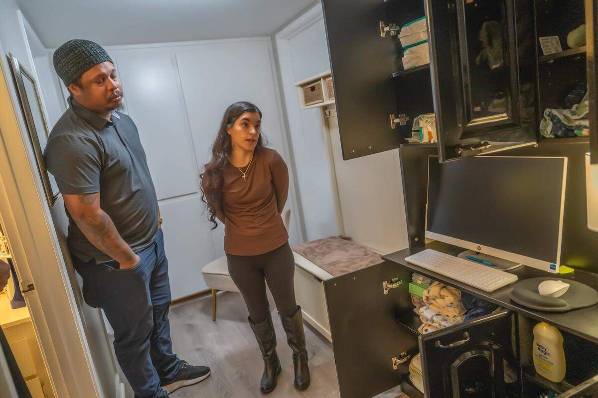 Rachel Harrison and her partner Marcell Johnson stand last month near a computer cabinet where they have hidden their baby’s toys and supplies because they were too painful to look at after she miscarried in September.