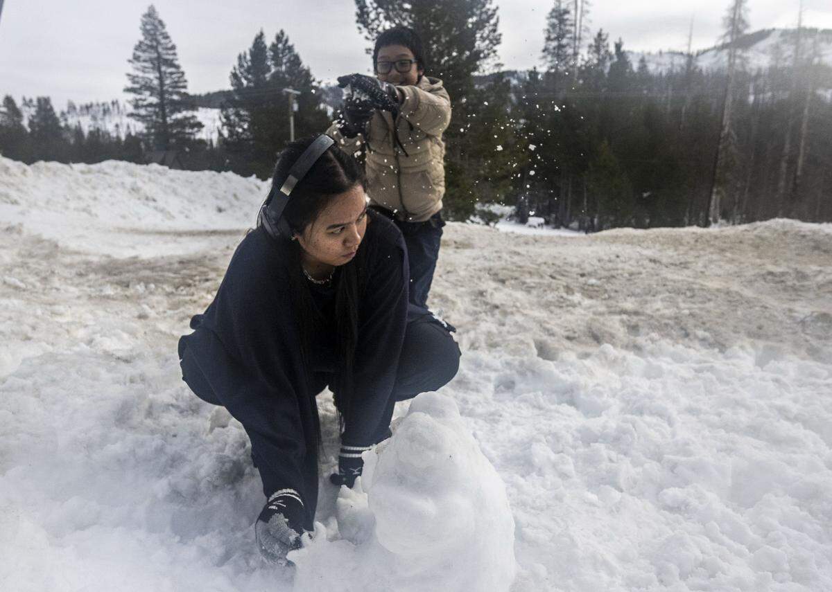 Aerion Daguman, 21, of Stockton, gets a dusting of snow from her brother Maximus, 11, as she builds a snow bear near Phillips Station in El Dorado County on Tuesday.