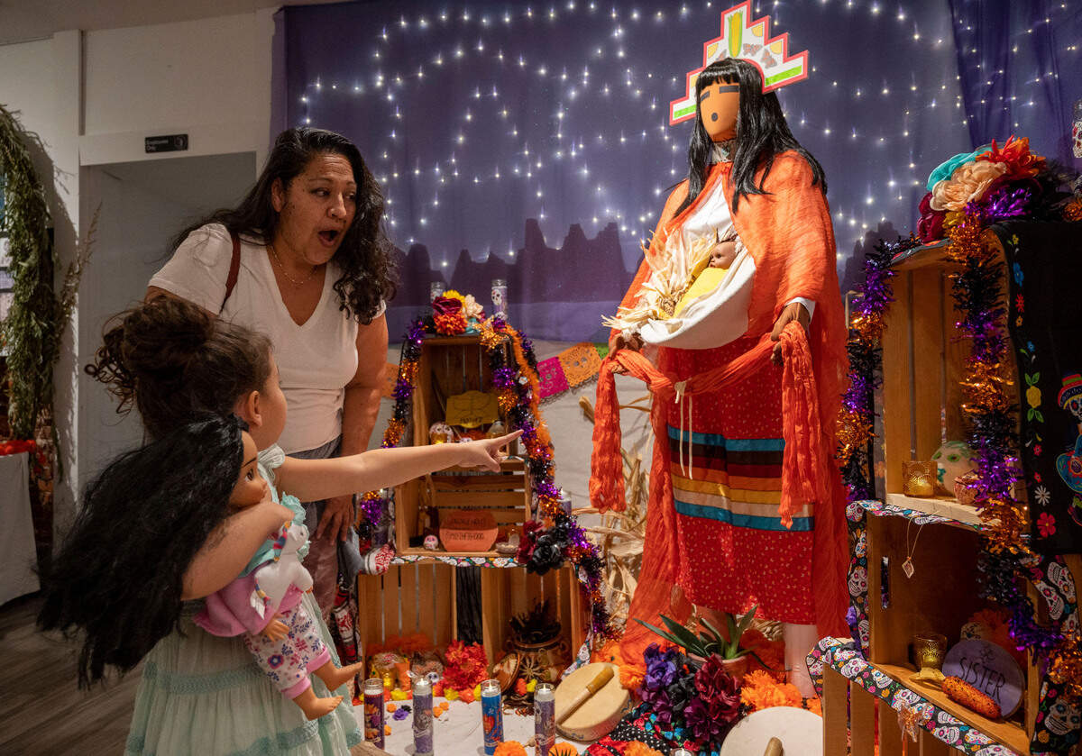 Luli Velasco and her daughter Maizie, 5, look over the ofrenda altar they worked to honor corn maiden and their ancetors at a reception at the Center Street Gallery on Thursday, Oct. 19, 2023, for Placerville’s Dia de los Muertos celebration.