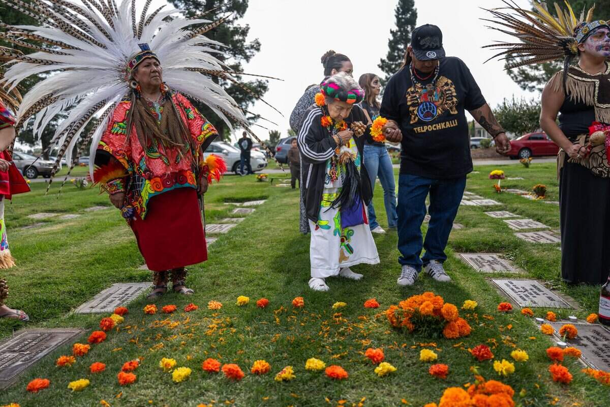 Angelbertha Cobb, center, bows in respect near where her son Joseph Cobb Sr. is buried as she participates in the Dia de los Muertos observance on Thursday at St. Mary’s Catholic Cemetery in Sacramento.