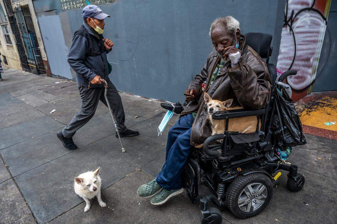 Vurnell Bullock, 70, navigates the sidewalks in the Tenderloin neighborhood of San Francisco with his dogs Zoey, left, and Max in his wheelchair on Oct. 12. He lives in an SRO nearby.