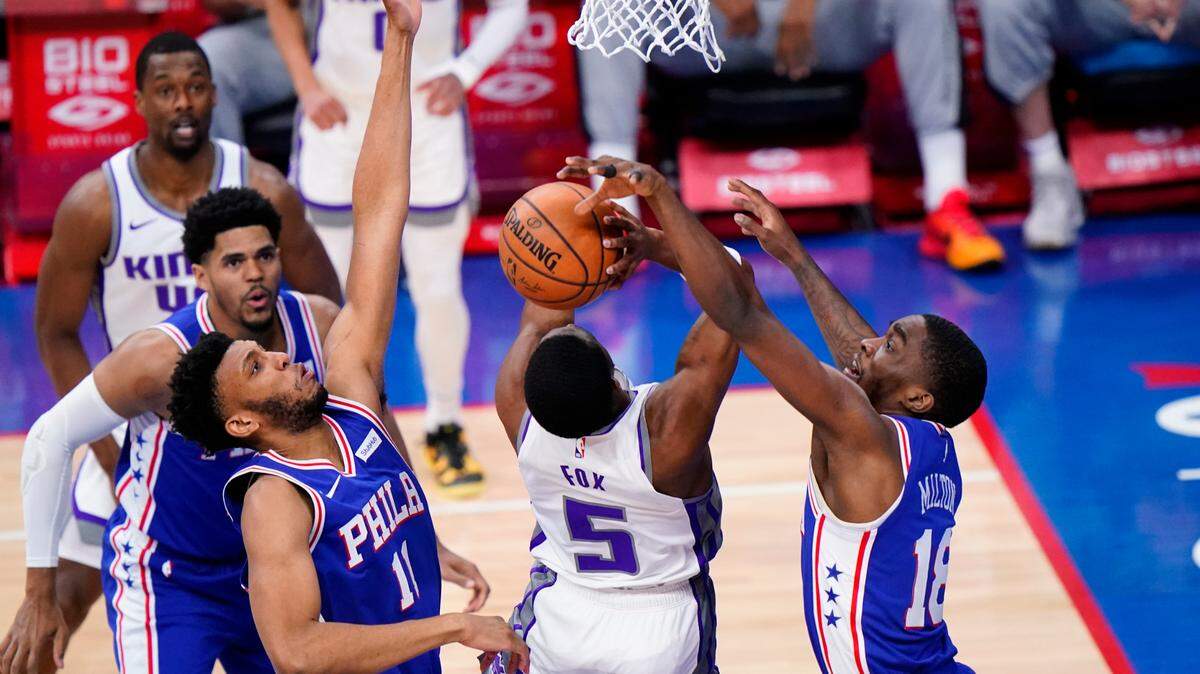 Sacramento Kings’ De’Aaron Fox (5) tries to get a shot past Philadelphia 76ers’ Shake Milton (18) and Tony Bradley (11) during the first half of an NBA basketball game, Saturday, March 20, 2021, in Philadelphia. (AP Photo/Matt Slocum)