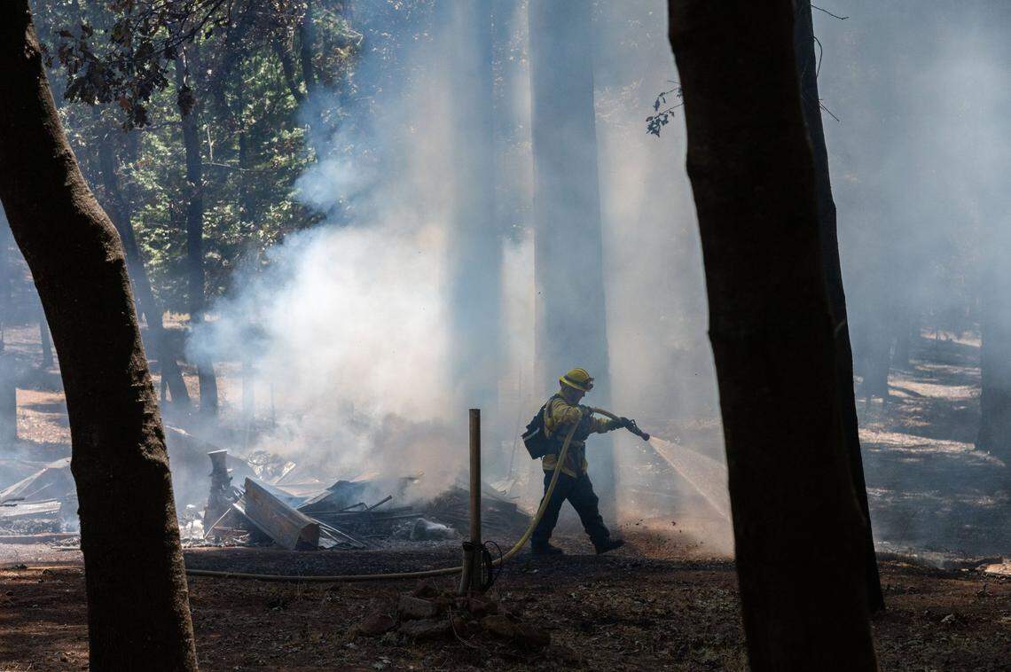 A firefighter with the Monterey Fire Department hoses down smoldering rubble in Cohasset on Friday. A group of firefighters put out hot spots to prevent fires from further damaging remaining structures in the area.
