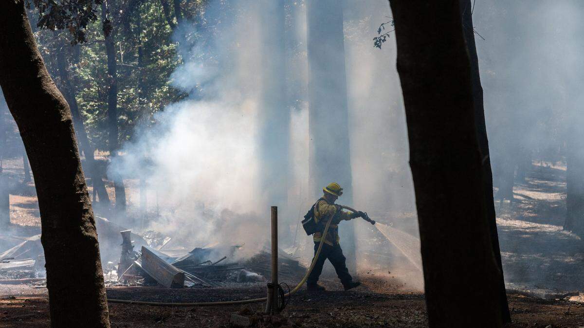 A firefighter with the Monterey Fire Department hoses down smoldering rubble in Cohasset on Friday, July 26, 2024. A group of firefighters put out hot spots to prevent fires from further damaging remaining structures in the area.