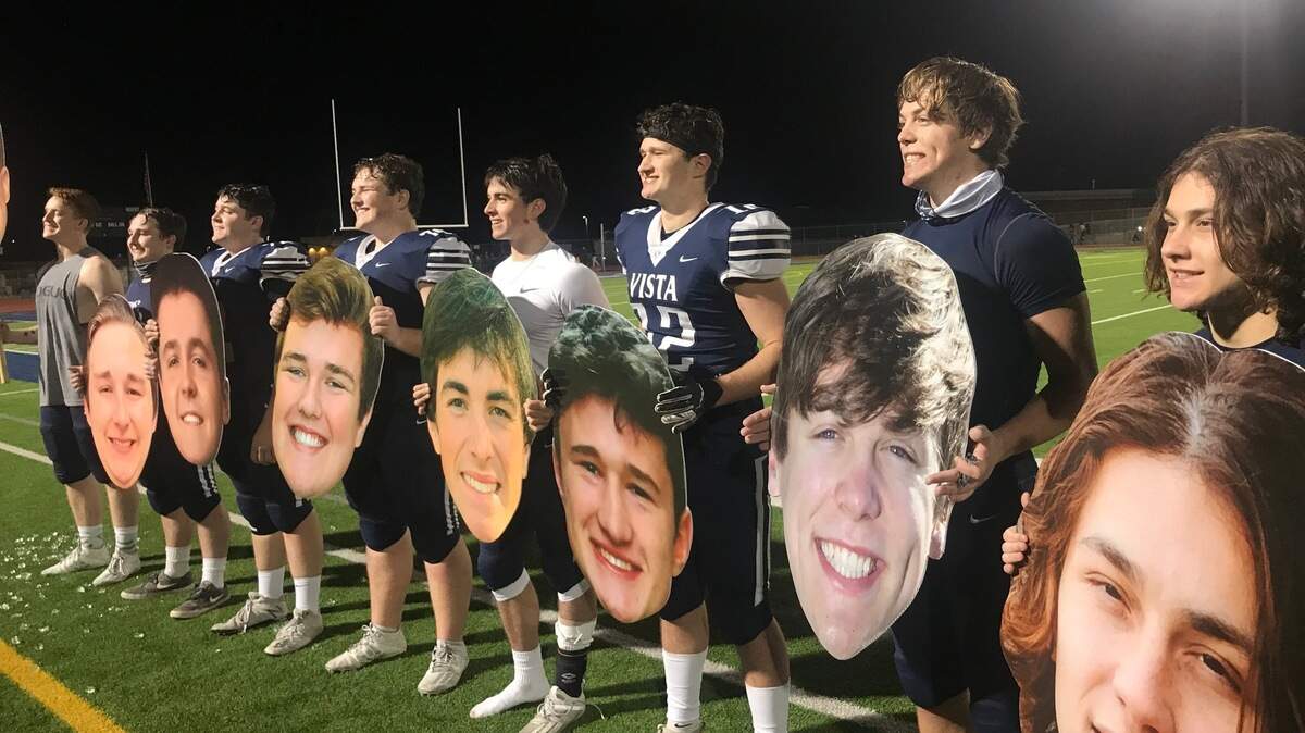 Vista del Lago football players hold cutouts with their faces on them after taking a 40-31 win over Inderkum on Friday night.