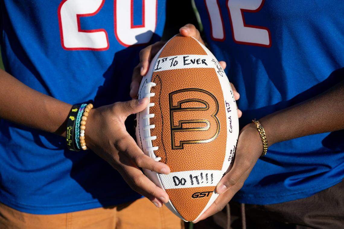 Twins Devin and Dana Gree, the Sacramento Bee Flag Football Players of the Year, hold an autographed game football at Christian Brothers High School in Sacramento on Monday. It reads “1st to ever do it,” a reference to the team’s Division II section championship in the sport’s first official season.