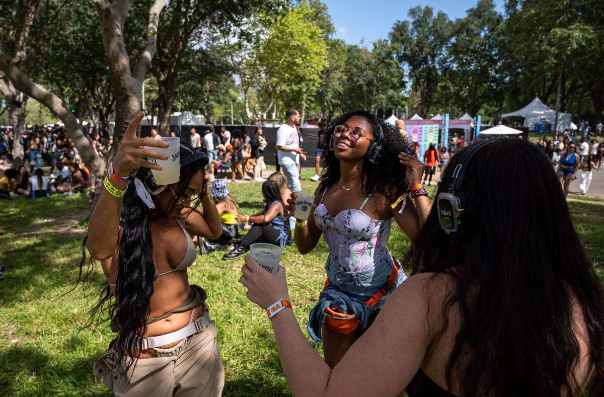 Festival-goers and friends, from left, Elissa Yu, of Los Angeles, Carmen Banks, of San Francisco, and Olivia Levine, of Sacramento dance to a silent disco beat on wireless headphones between acts on the first day of the Sol Blume music festival at Sacramento’s Discovery Park on Saturday, April 30, 2022. 