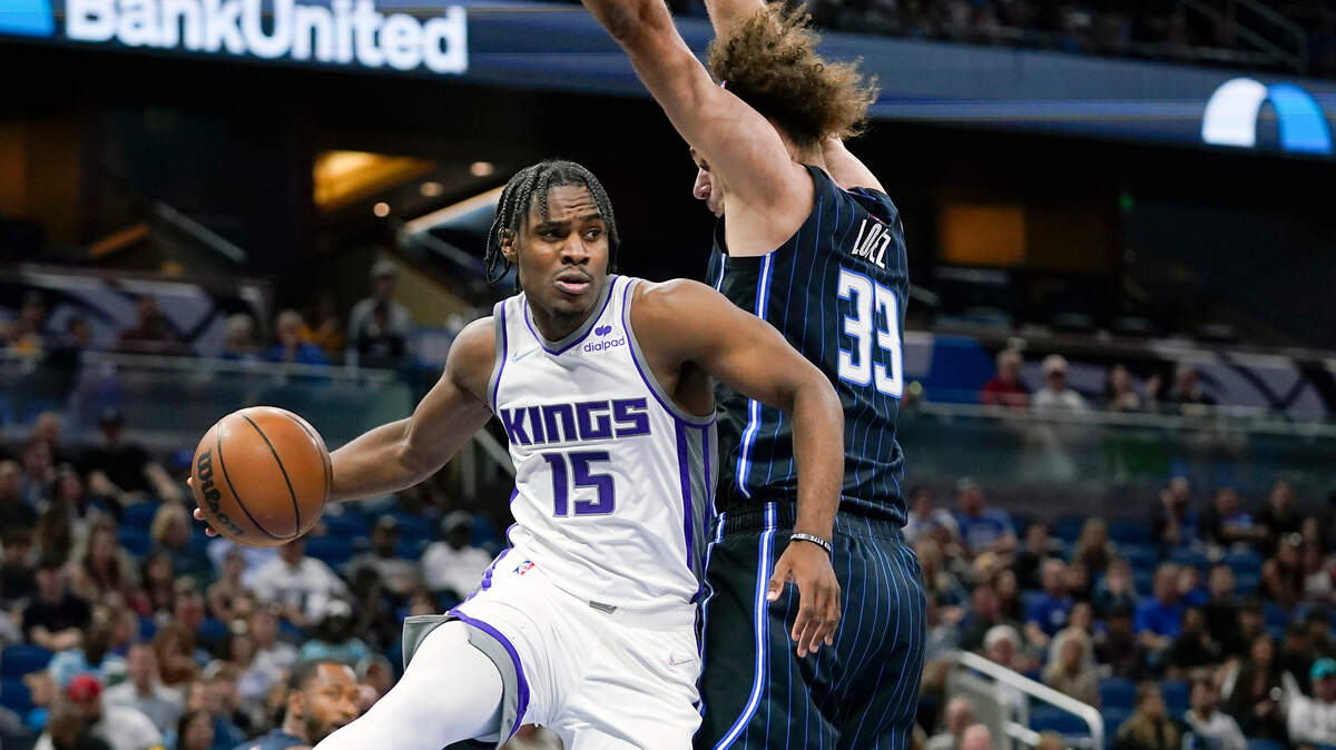 Sacramento Kings guard Davion Mitchell (15) passes the ball as his path to the basket is blocked by Orlando Magic center Robin Lopez (33) during the first half of an NBA basketball game, Saturday, March 26, 2022, in Orlando, Fla. (AP Photo/John Raoux)