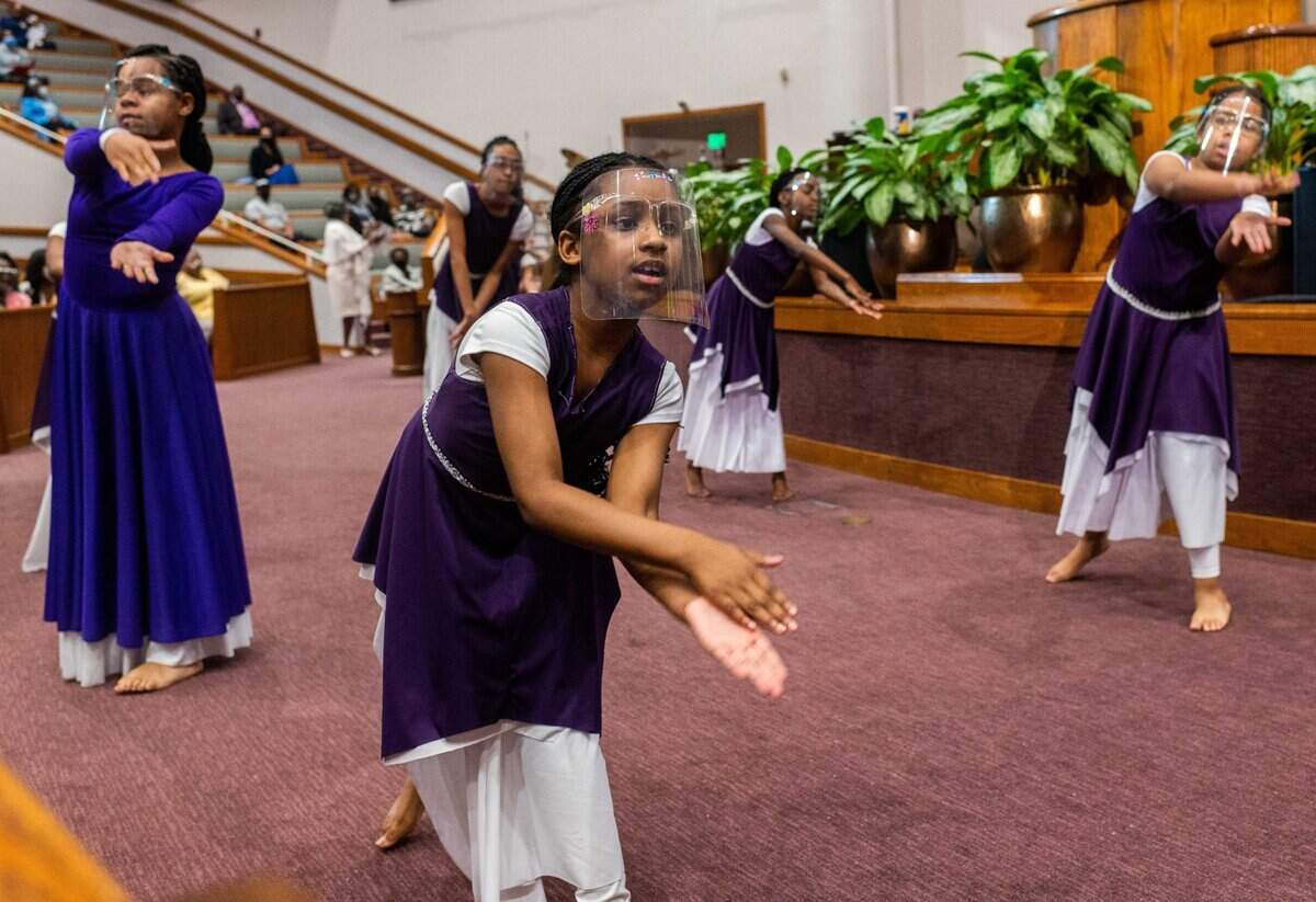 Children dance while wearing face shields during a play reenacting the death and the resurrection of Jesus Christ at St. Paul Missionary Baptist Church in Oak Park in Sacramento on Easter Sunday.
