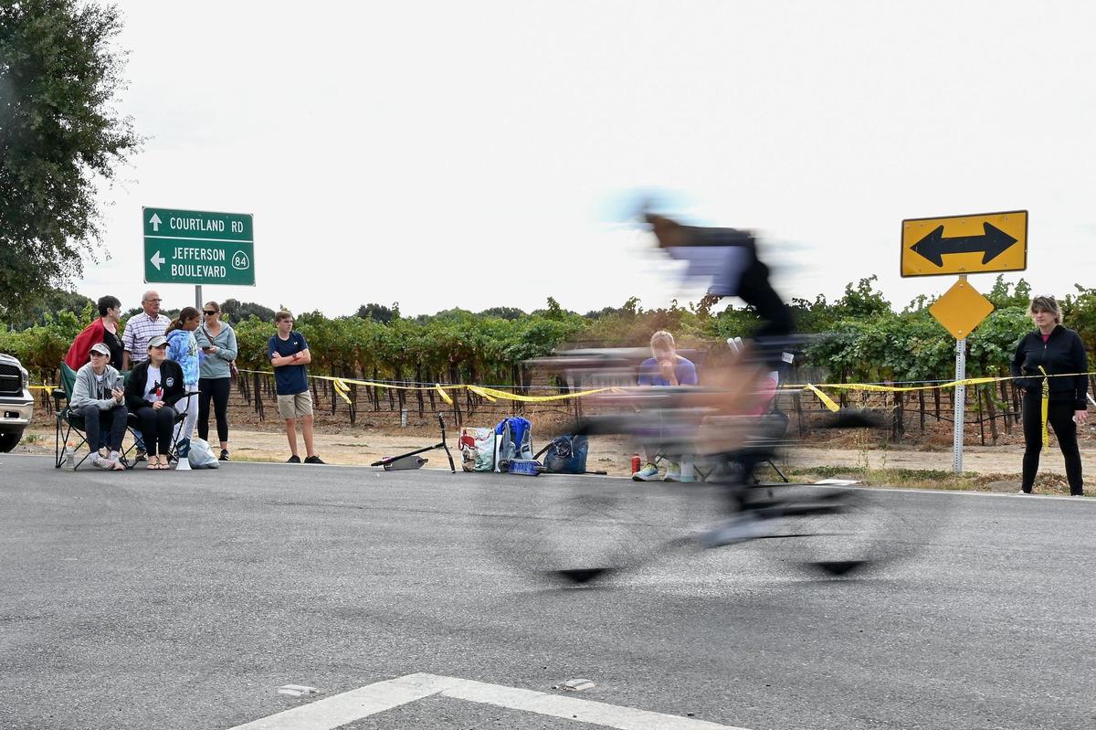 A triathlete rides by people waiting for their family members at about the 38-mile marker of the bike course during the Ironman California triathlon on Sunday.