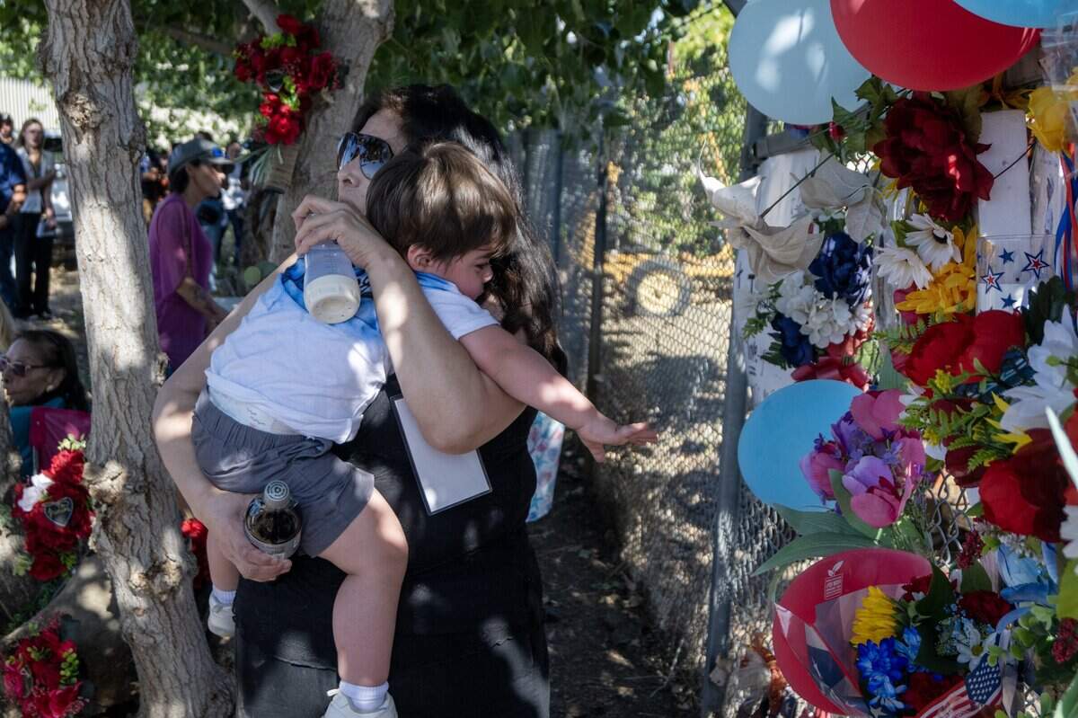 Lupe Melendez holds her grandson Luciano Melendez on Wednesday as he reaches for a photograph of his father at a memorial for the seven men who died in the fireworks explosion in Esparto on the first anniversary of the event.