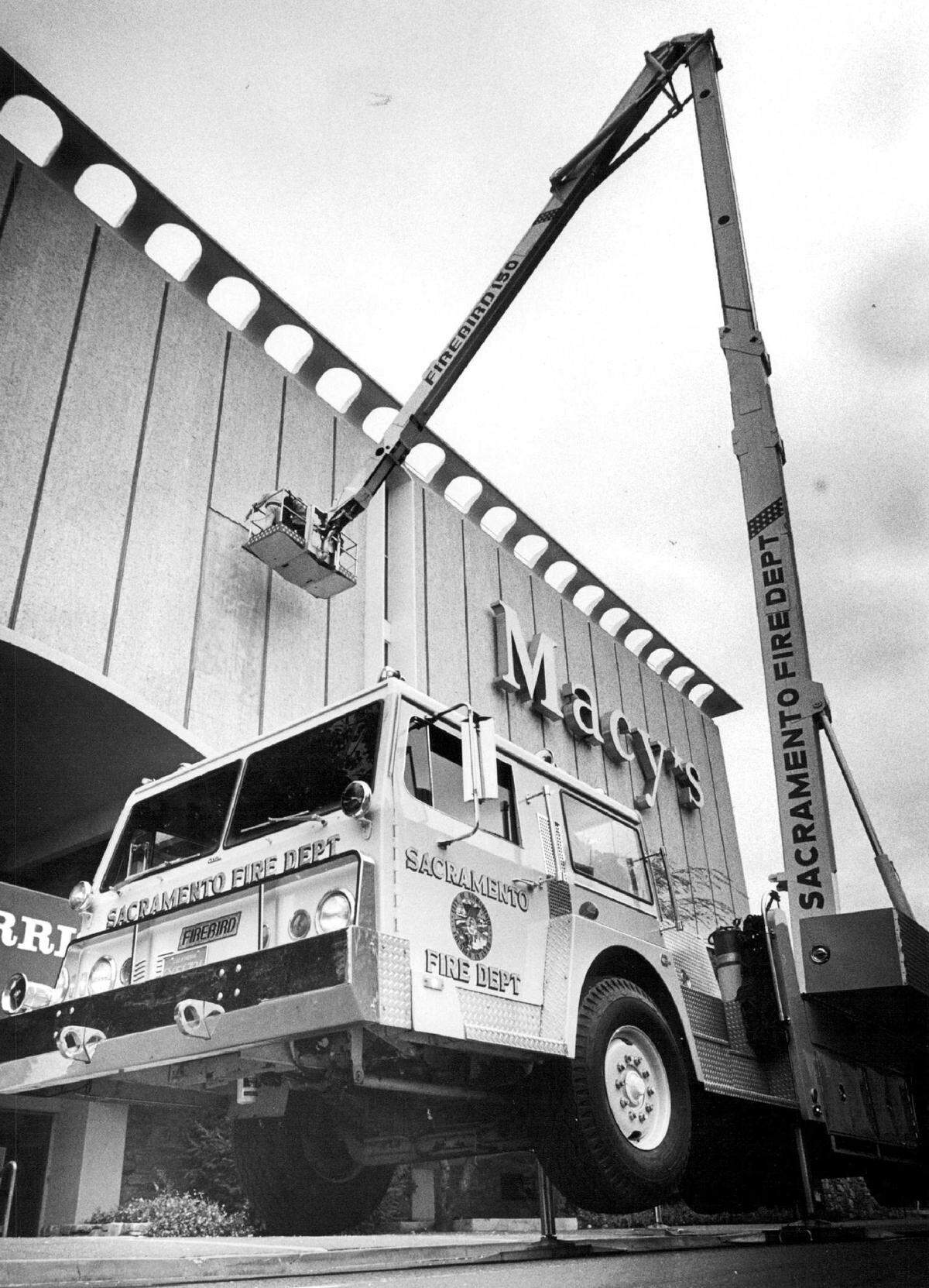 The Sacramento Fire Department’s ‘firebird” crane is used to check out loose files – some of which were blown free by winds – on the downtown Macy’s building in 1982.