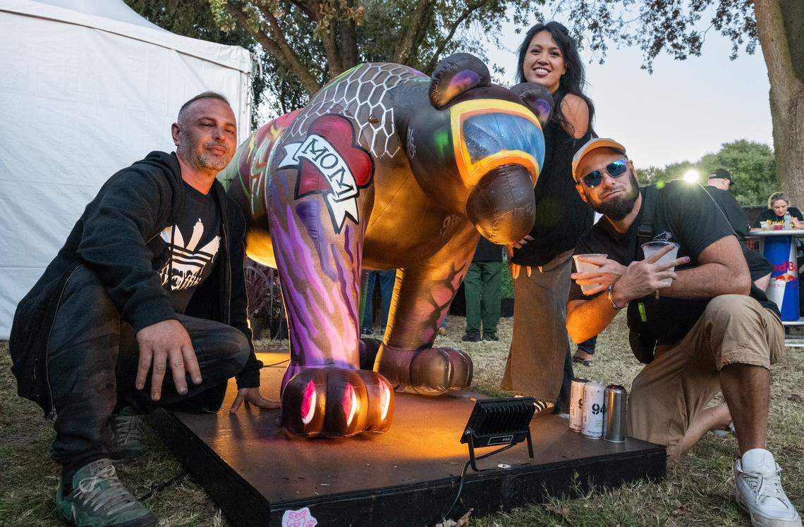 Sacramento muralists Daniel Pedersen, left, Mindy Galloway and Brandt Rock pose with an inflatable bear that they painted during the Aftershock festival on Friday, Oct. 3, 2025, in Discovery Park in Sacramento. 