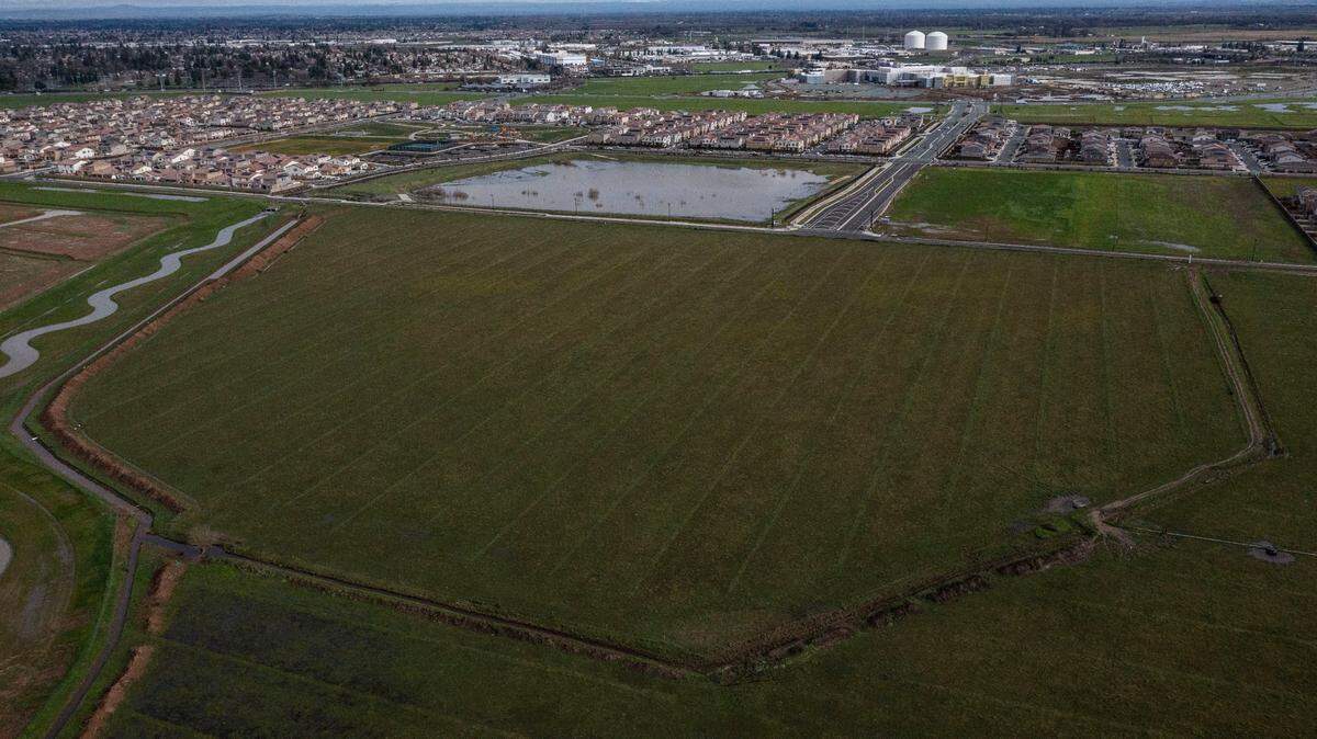 An aerial view shows the proposed Elk Grove site for the Sacramento Zoo in the foreground on Tuesday, Dec. 28, 2021, with newly constructed Lotz Parkway crossing the middle of the image. New homes and the under construction Sky River Casino are visible in the distance. The zoo would be accessed from Highway 99 via Kammerer Road.
