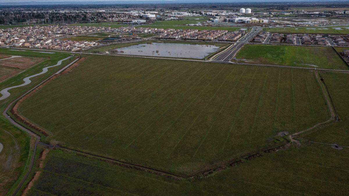 An aerial view shows the proposed Elk Grove site for the Sacramento Zoo in the foreground on Tuesday, Dec. 28, 2021, with newly constructed Lotz Parkway crossing the middle of the image. New homes and the under construction Sky River Casino are visible in the distance. The zoo would be accessed from Highway 99 via Kammerer Road.
