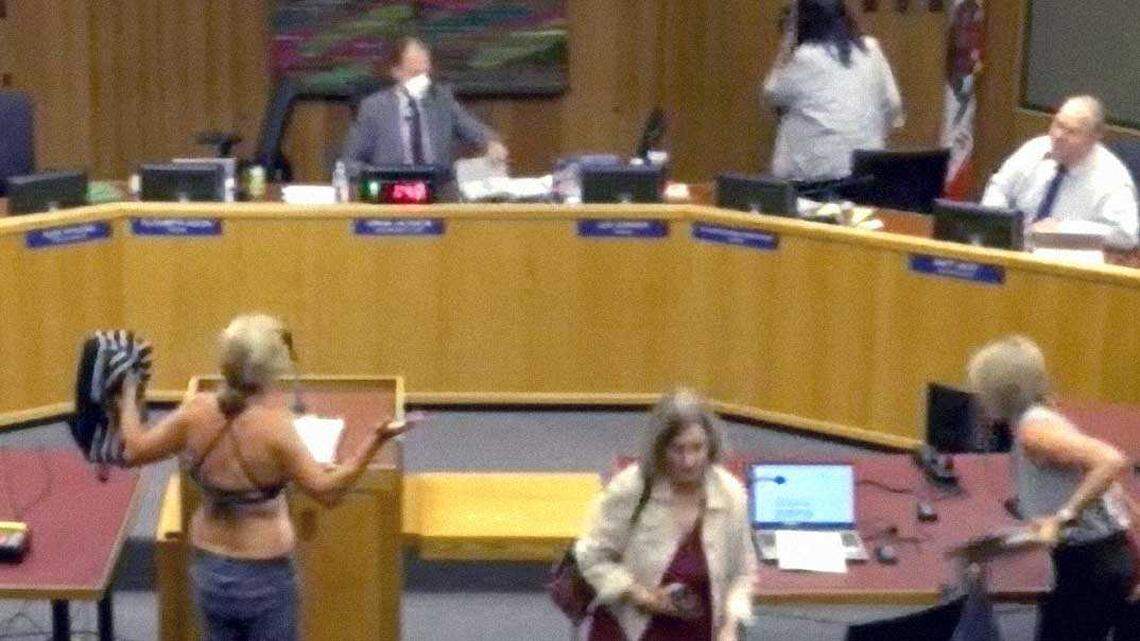 Beth Bourne removes her shirt to reveal a bathing suit while speaking at the Davis Joint Unified School District board meeting on Sept. 18. The board twice recessed the meeting after Bourne attempted to disrobe during public comment to protest district policies on transgender students' access to locker rooms.