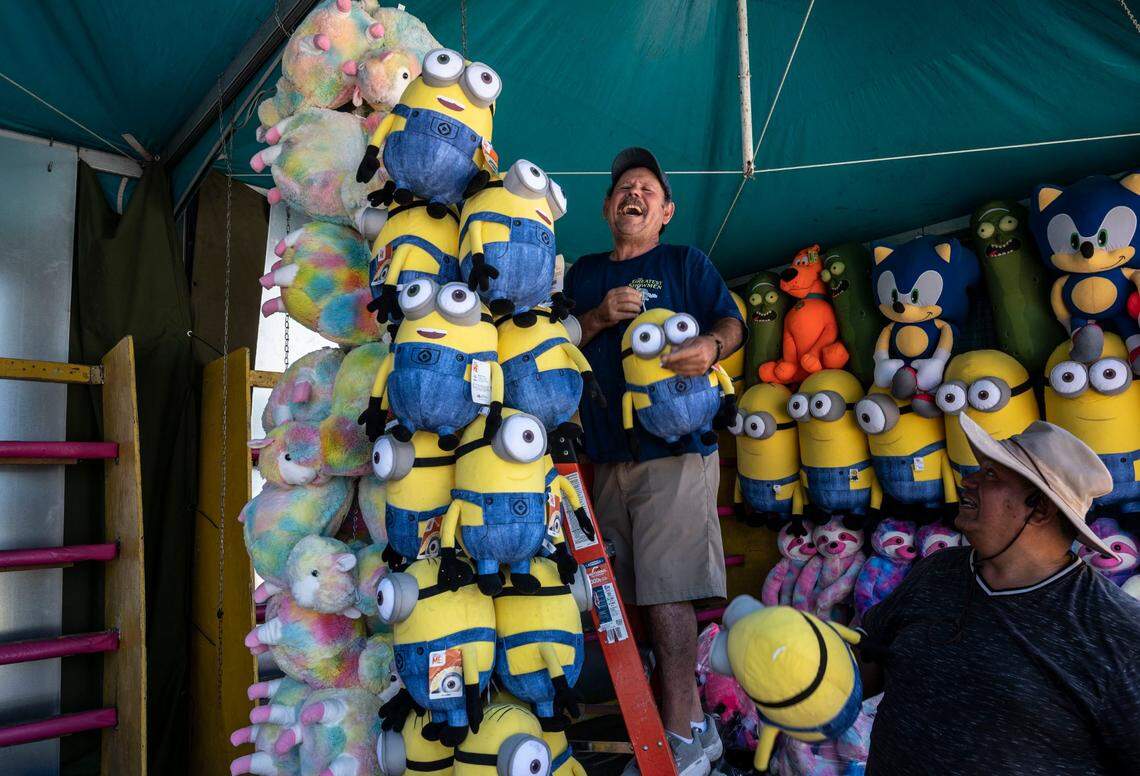 Victor Lopez, left, of Phoenix and David Perez, of Riverside, both with Butler Amusement Inc. stock prizes at a bottle-breaking carnival game during while setting up Wednesday for the California State Fair. The fair reopens Friday for the first time since the pandemic and runs through July 31.