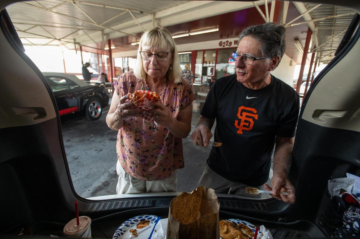 Barbara and John Swentowsky eat chili cheese burgers from the back compartment of their vehicle at Lou’s Burgers on Friday in North Highlands. John said he has been eating there since the 1960s.