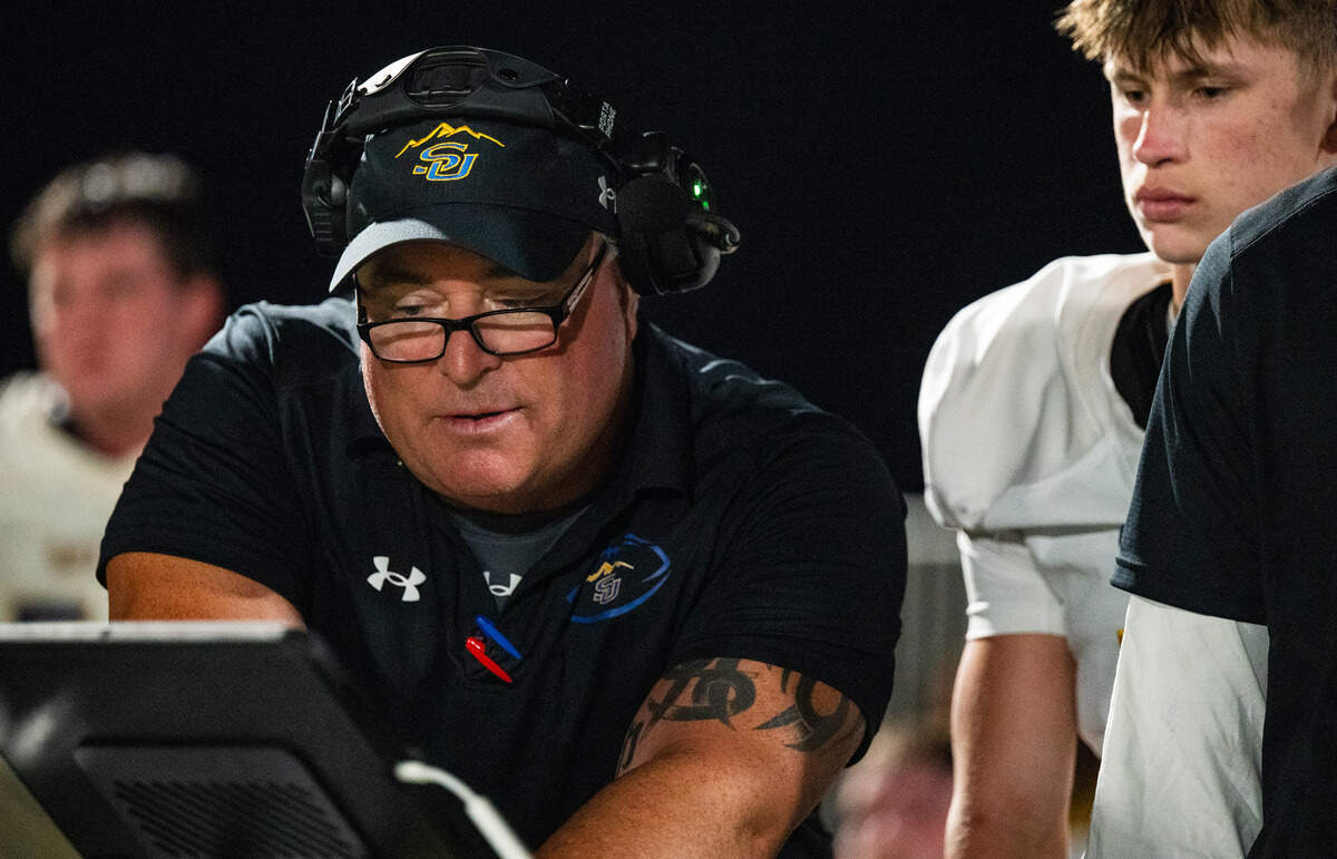Sutter coach Ryan Reynolds reviews video on the sideline with wide receiver Hayden Azevedo as their team plays the Bradshaw Christian Pride in Vineyard on Friday.