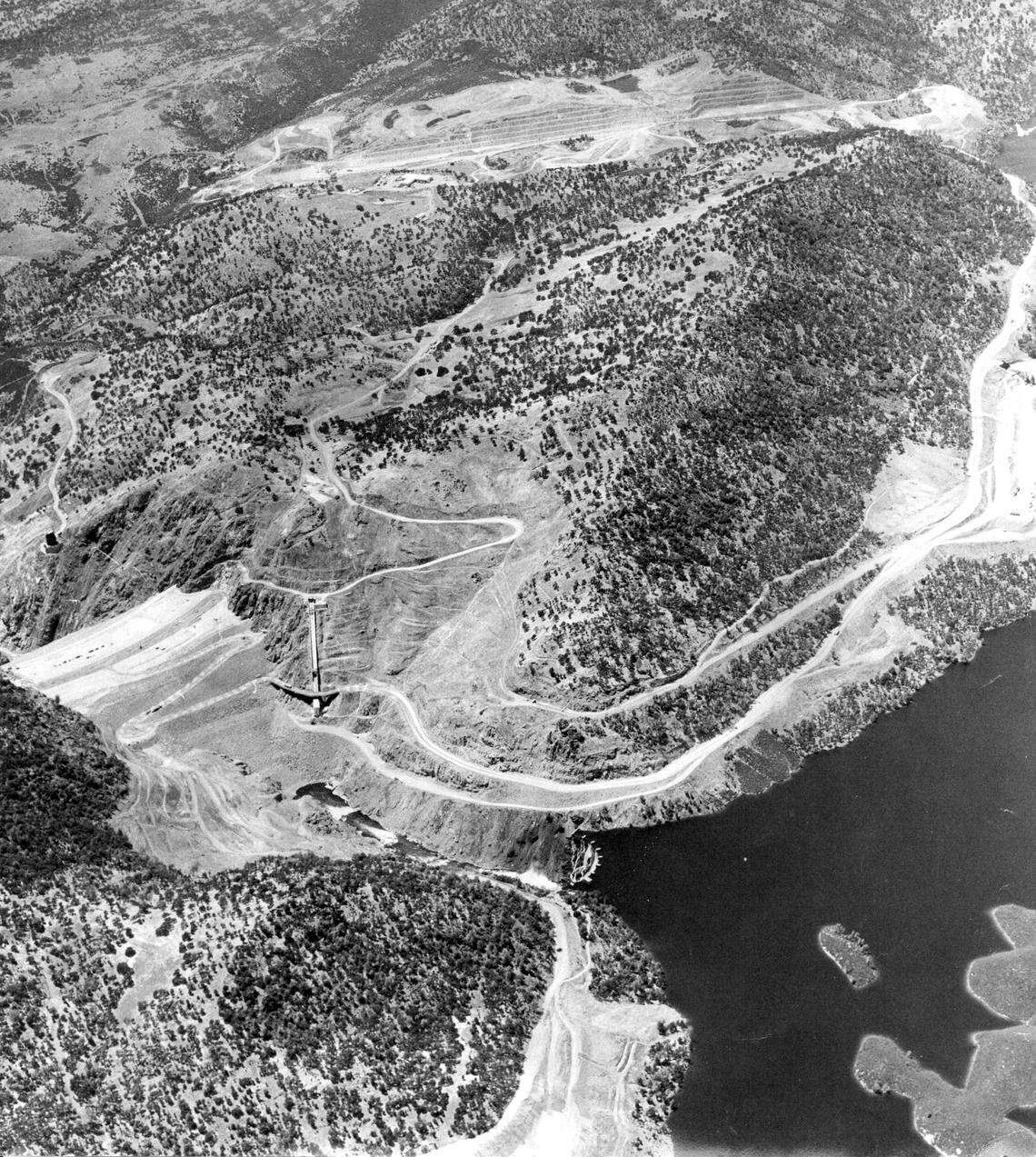 Water spills over the old Melones Dam, built in 1928, in the foreground, as New Melones Dam takes shape in this June 2, 1978 aerial photo. A top, the new spillway is being cut into mountain. The project first approved by Congress in 1944, but not completed until the late 1970s. It was the last major dam built in California.