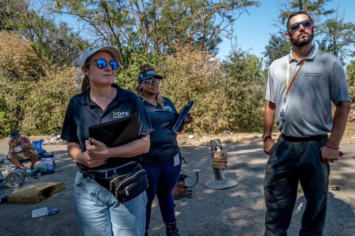 Jennifer Cohen, left, Alanna McWilliams, center, with Hope Cooperative and Christopher Foxall, right, with the city of Sacramento Department of Community Response, canvass a homeless encampment known as “the snake pit” to offer services and pass out water in Sacramento on Thursday.