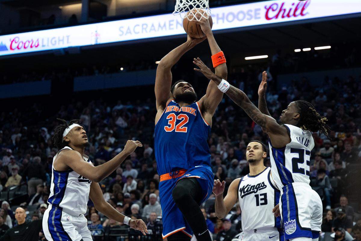 New York Knicks center Karl-Anthony Towns (32) drives to the basket against Sacramento Kings guard Keon Ellis (23) and forward Keegan Murray (13) during a NBA game at Golden 1 Center on Monday, March 10, 2025, in Sacramento.