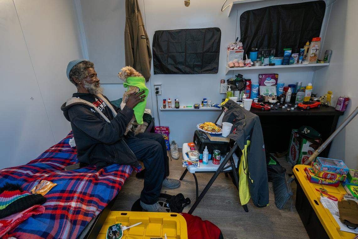 Terry Swilley, 60, lifts his dog, Lala, inside his tiny home at Sacramento County’s Stockton Boulevard Safe Stay Community in December. Denied housing elsewhere because of his dog, Swilley said he is grateful to keep her with him and appreciates the wellness checks, laundry service and meals at the shelter. “Staying here has really saved my life,” said Swilley.