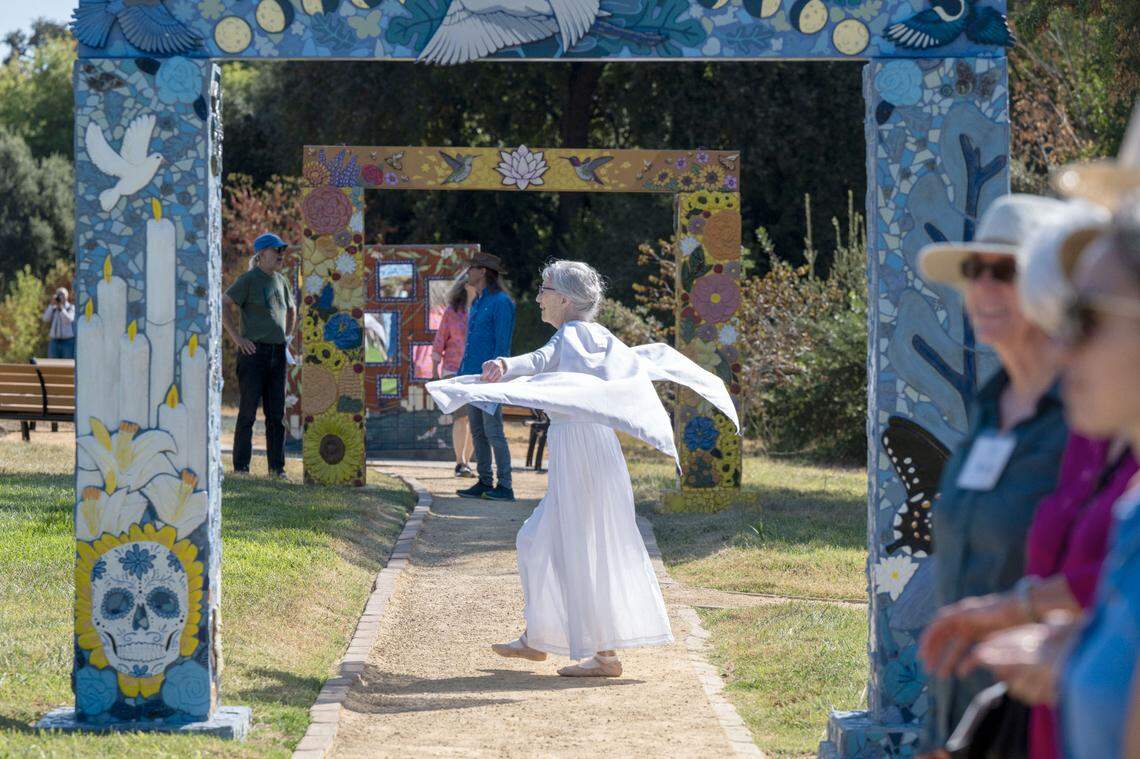Allegra Silverstein, the city of Davis’ first poet laureate, dances with white wings as a member of the Threshold Singers as the Davis Cemetery District dedicates a permanent COVID-19 memorial on Sunday.