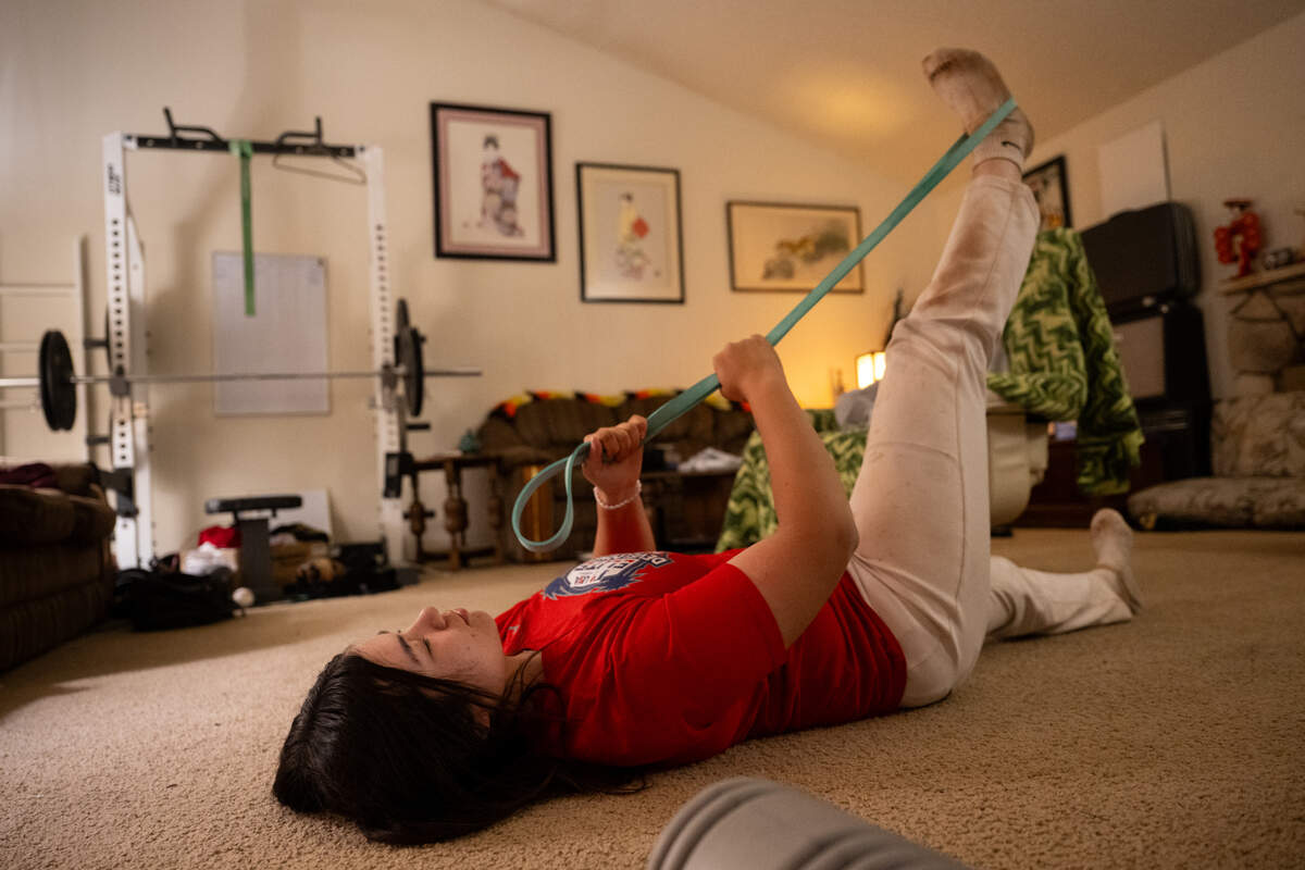 Laney Fukuoka does her stretching routine at home in Sacramento on Thursday after a practice to help keep in top physical form. Fukuoka pitches and plays first base for the Kennedy Cougars varsity baseball team.