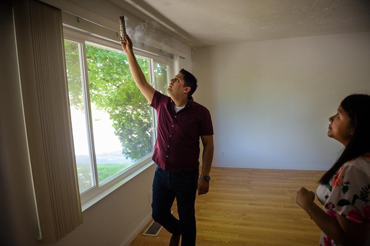 Andrew Llorente burns sage to purify their new home with his wife, Farrah Poladi, on Sunday, May 6, in Carmichael.