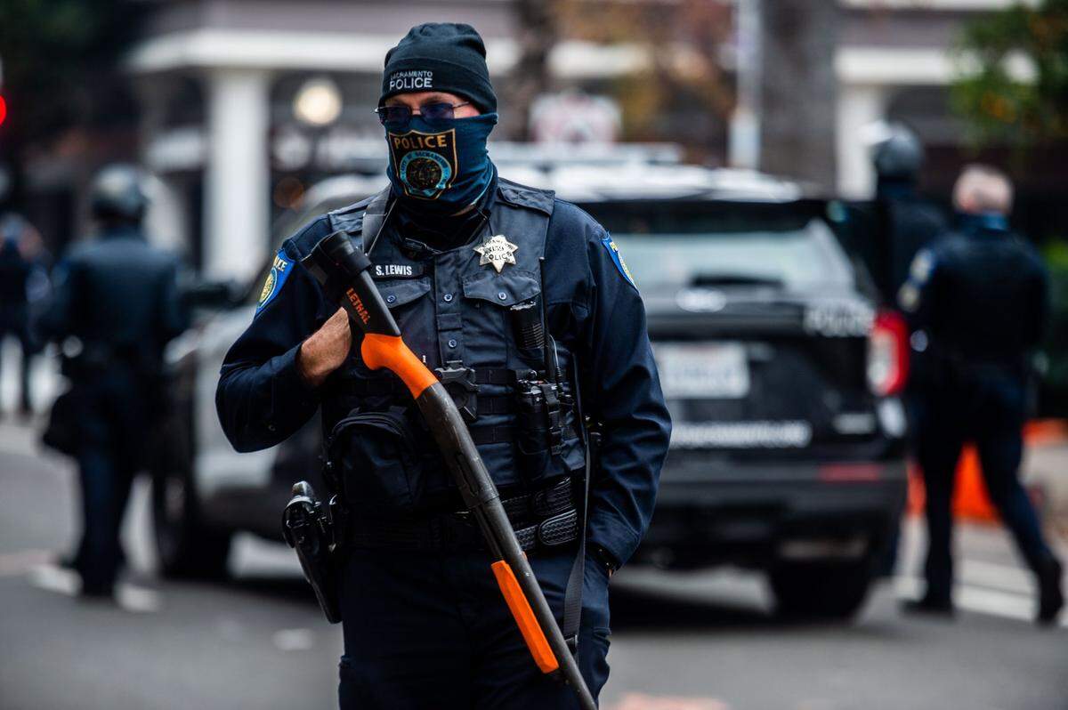 A Sacramento police officer holds a less lethal crowd control weapon at the state Capitol on Wednesday, Jan. 6, 2021, during a pro-Trump protest as a riot in Washington, D.C. delayed the certification of President-elect Joe Bidens victory.