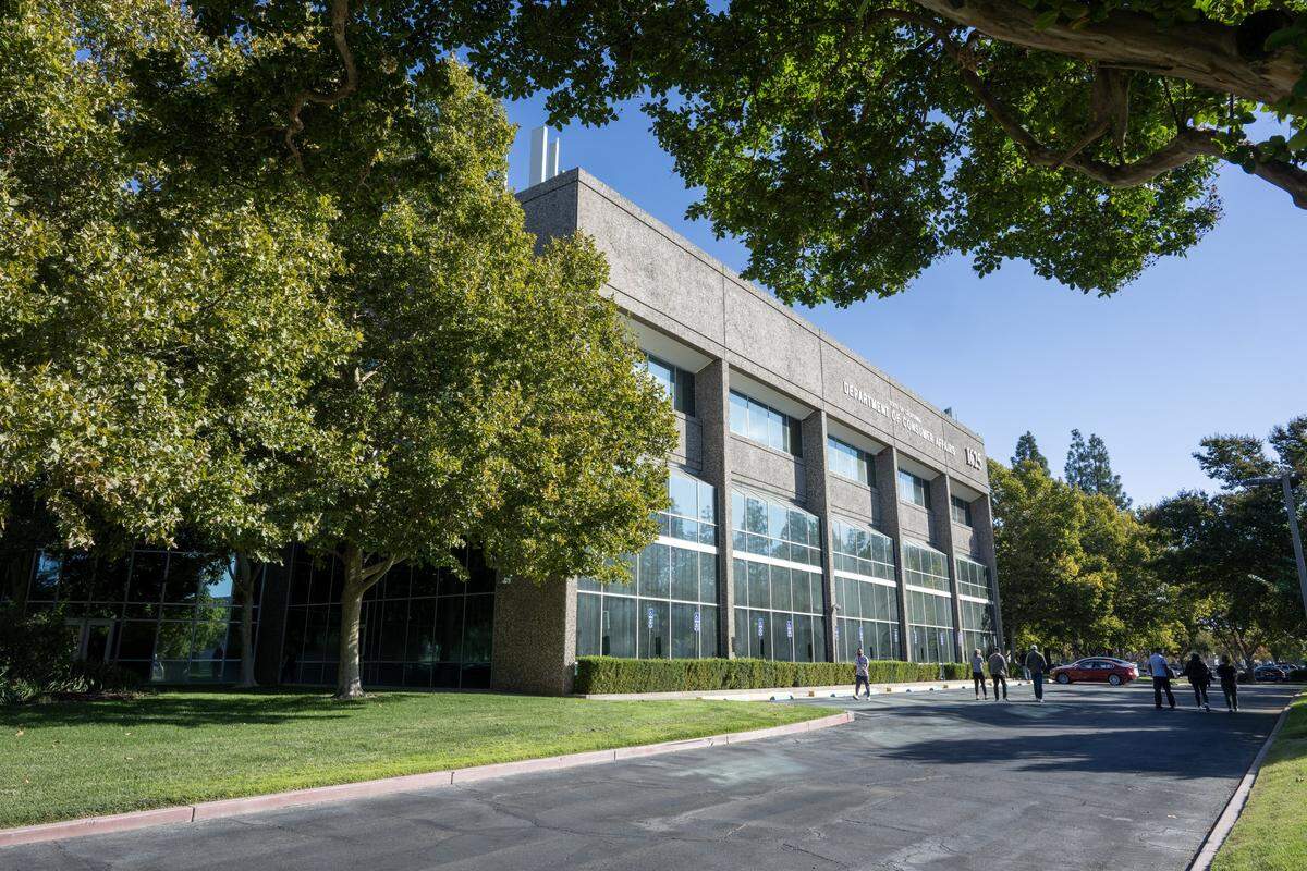 People stand in the parking lot of the California Department of Consumer Affairs office in Natomas earlier this month. The building served as the original Arco Arena when the Sacramento Kings first moved to the city. 