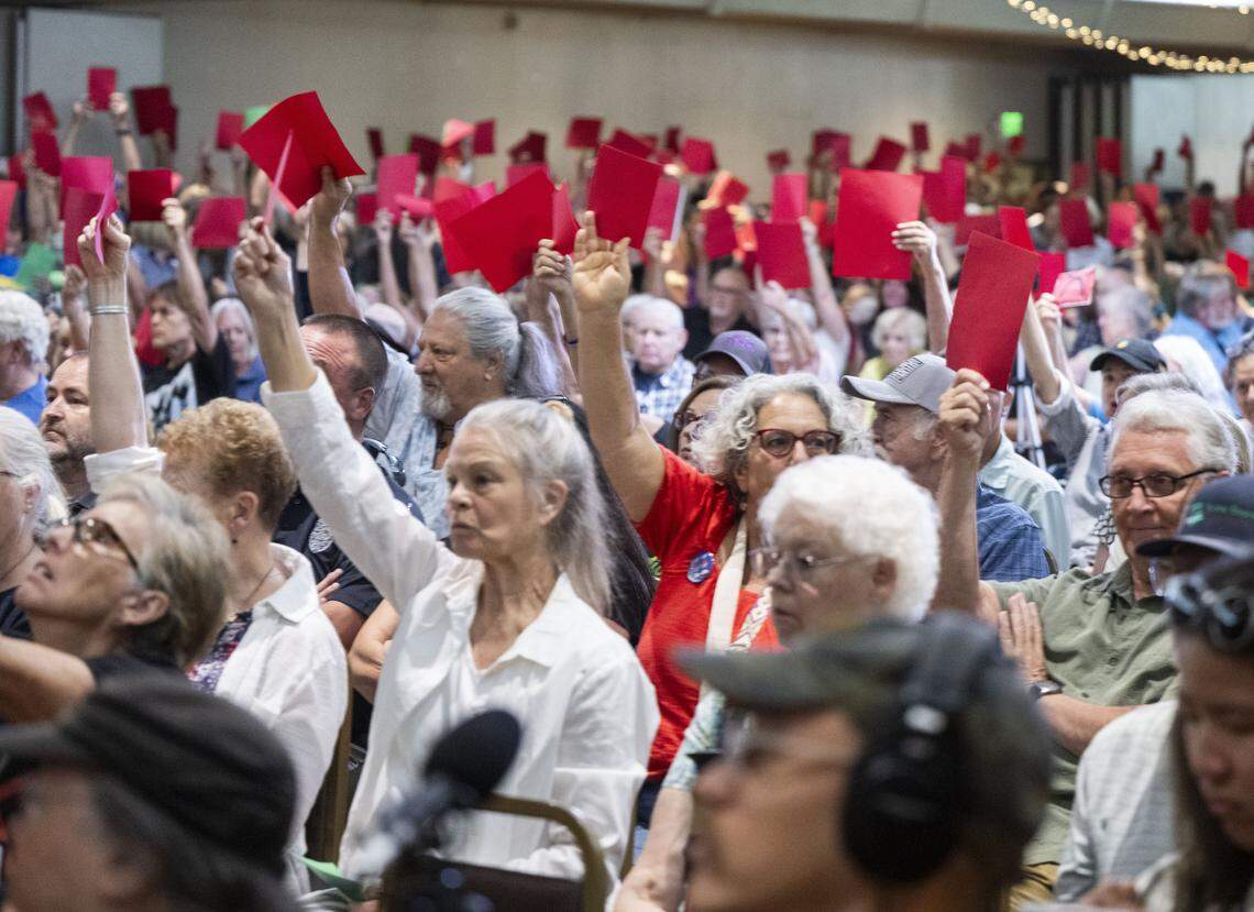 Participants hold red cards in disapproval of a statement by Rep. Doug LaMalfa, R-Oroville, during a town hall meeting on Monday in Chico.
