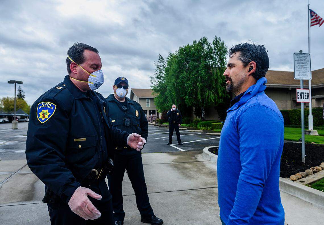 Lodi Police Capt. Sierra Brucia, wearing a mask and gloves, meets with Pastor Jon Duncan outside the Cross Culture Christian Center on Palm Sunday, April 5, 2020, before the church canceled its services after its landlord locked the building on orders from the county’s public health officer.