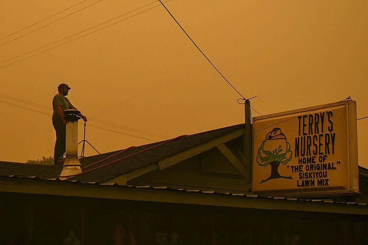 Dustin Brown waters the roof using a sprinkler at his father’s business, Terry’s Nursery, on Highway 263 in Yreka as the McKinney Fire burns in Klamath National Forest on July 31. “I’m not losing this,” said his father Terry Brown. “I’ve owned it for 46 years.”