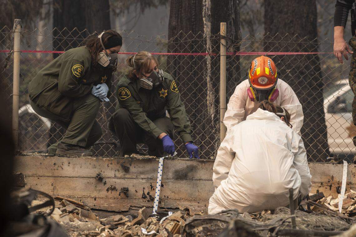 Fresno Sheriff’s deputies, left, and El Dorado County search and rescue teams look for a body on West Park Drive in Magalia in November 2018 after the Camp Fire destroyed homes in the area.