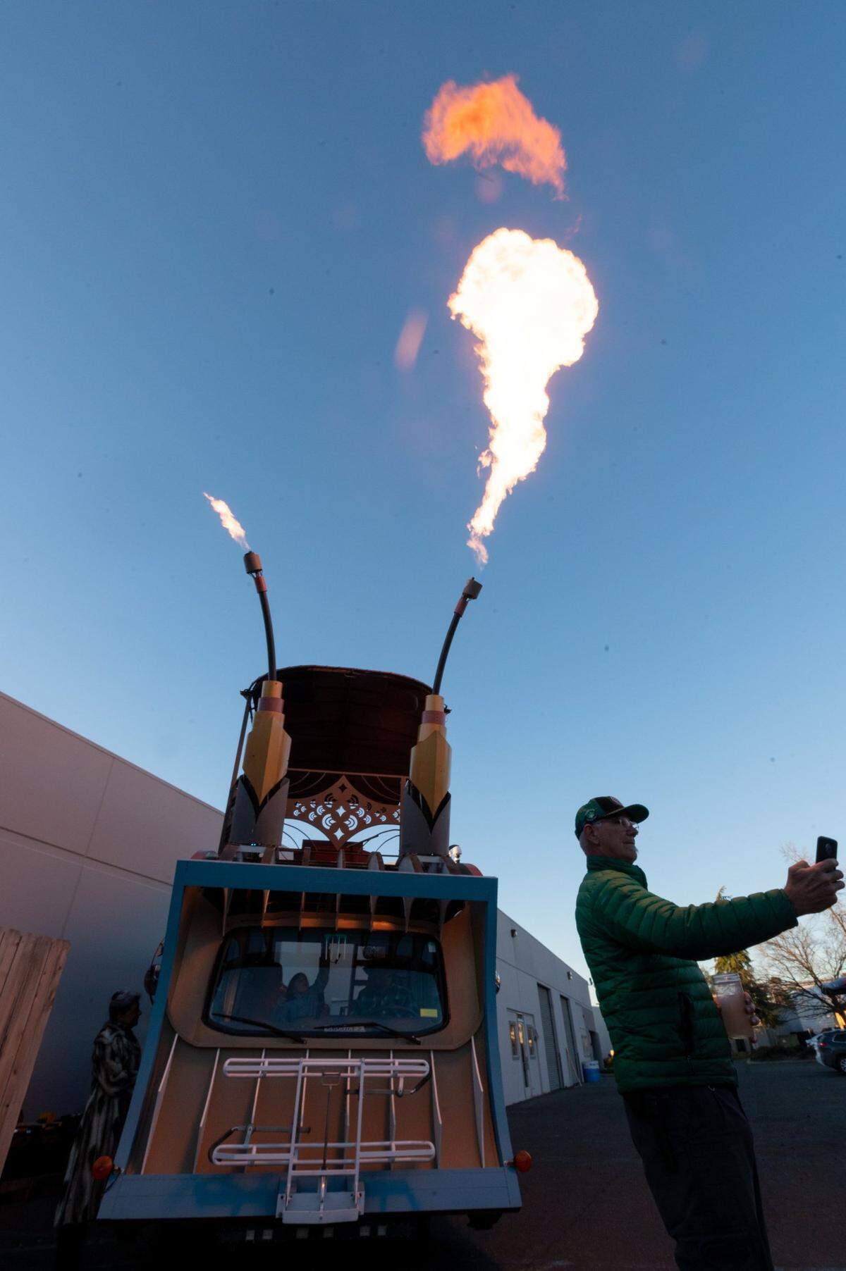 Chris Coburn takes a selfie as flames shoot out of 18-foot tall float called DecoFish on Wednesday, Feb. 16, 2022 in Diamond Springs. The float creators Andy Tannehill and Kimberly Medici will participate in the Mardi Gras-inspired City of Trees Parade in Sacramento on Feb. 26.