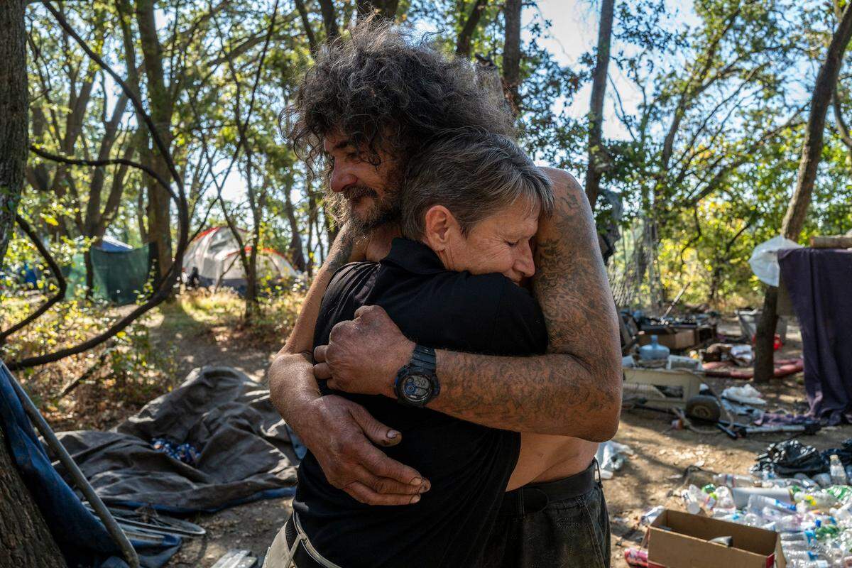 Tracey Knickerbocker, a case worker for Hope Cooperative, hugs Jeff Fry earlier this month at a homeless encampment along the American River Parkway in Sacramento. The two were best friends and used to do meth together when she was homeless over ten years ago and lived on the “Island.” She said if it weren’t for people showing her kindness when she was homeless, she may not have made it back to the “real world.”