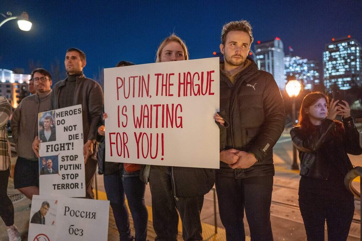 A sign alleges that Russian President Vladimir Putin has committed war crimes during a candlelight vigil in downtown Sacramento on Tuesday to mourn the loss of Alexei Navalny, the Russian opposition leader who died in an Arctic penal colony earlier this month.&nbsp;