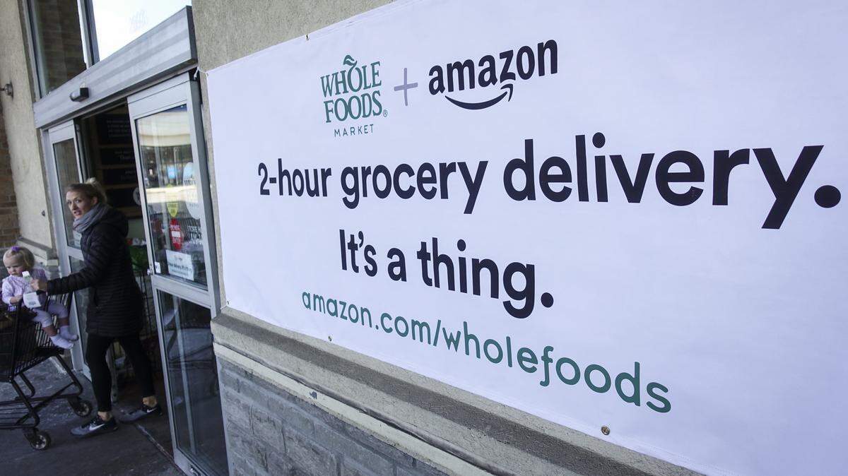 A sign promoting the Amazon Prime Now delivery service is displayed outside a Whole Foods store Feb. 8, 2018, in Cincinnati. Amazon, which owns Whole Foods, plans to roll out two-hour delivery at the organic grocer this year to those who pay for Amazon's $99-a-year Prime membership. Amazon launched the service is in Sacramento today. (AP Photo/John Minchillo)