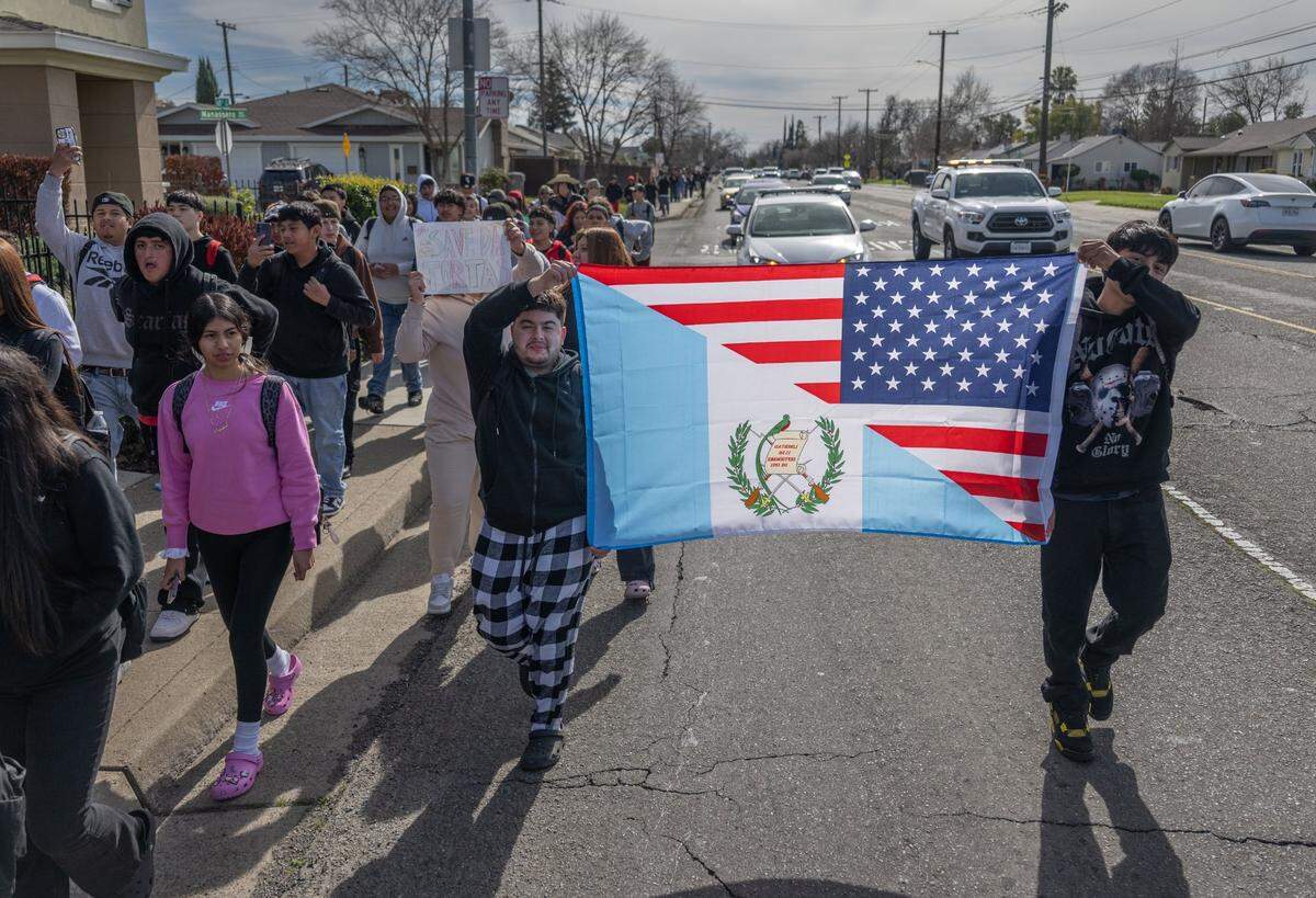 Students from Hiram Johnson High School in Sacramento carry a flag that combines designs from the Guatemalan and American flags during a February 2025 walkout to protest President Donald Trump. 