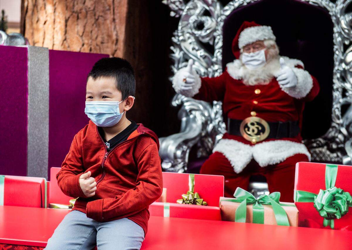 Temujin Vang, 5, of Sacramento poses for a pictures with Santa Claus as they social distance at Arden Fair mall on Sunday, Dec. 6, 2020. The mall’s annual Santa photo opportunity is contactless this year, and masks are required, because of the coronavirus.