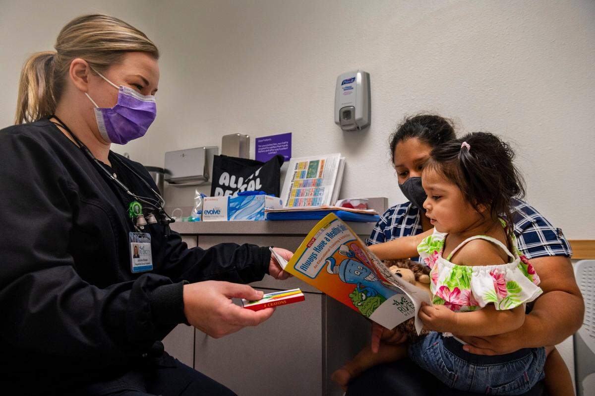 Dental hygienist Jennifer Bidwell, left, gives Maria Espinoza, center, and her daughter Angelic Mendoza Garcia, 18 months, materials at an appointment as a part of the Every Smile Counts program at Walton Pediatrics and Medical Associates in Sacramento on Thursday, July 9, 2020. Every Smile Counts is a test program that places hygienists in schools – currently closed because of coronavirus concerns – and pediatricians’ offices to make it easier for Medi-Cal patients to receive dental education and services.