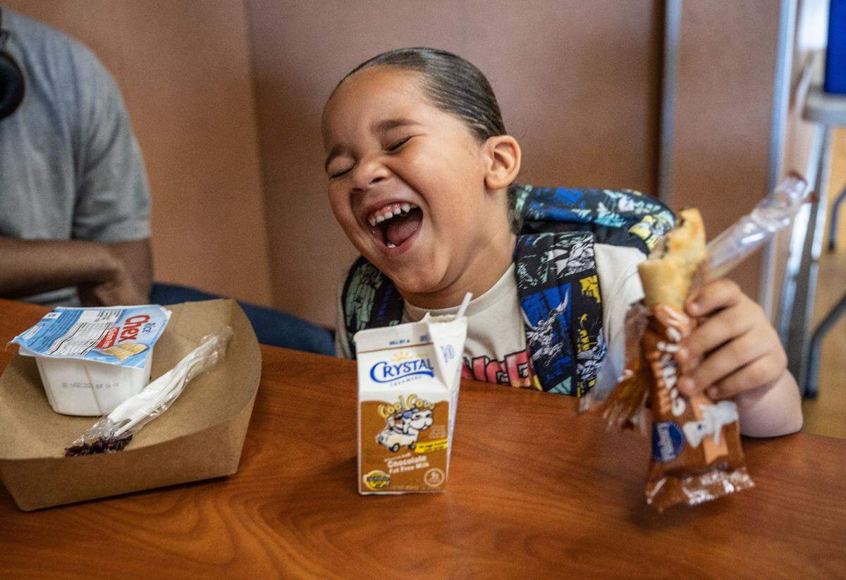 Kashis Lawson, 5, a student at Navigator Elementary, laughs with friends Tuesday as they have breakfast on the first day back to school.