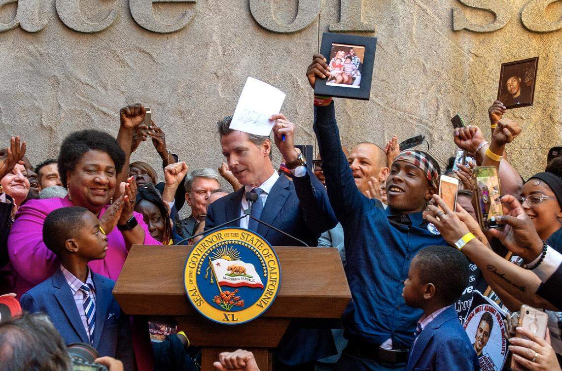 California Gov. Gavin Newsom holds up a copy of bill after signing it into law on Monday, Aug. 19, 2019.