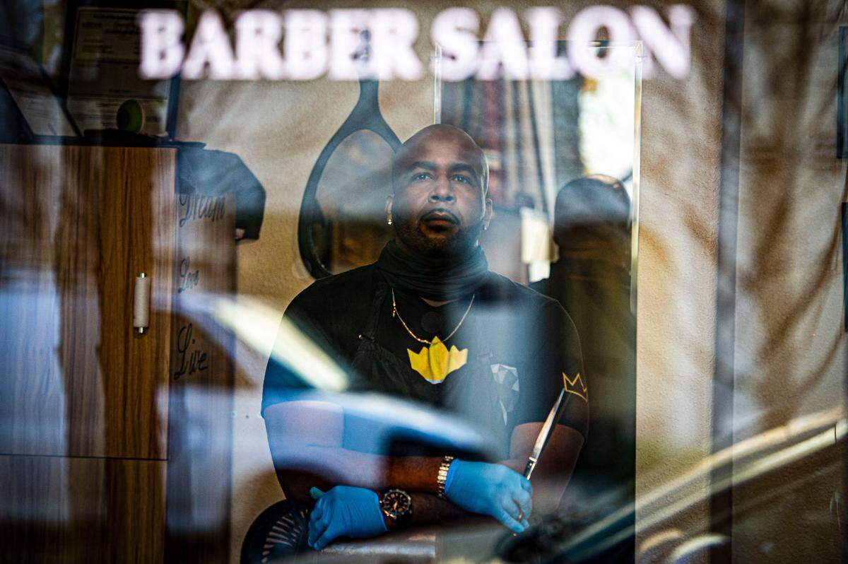 Hasheem Whitmore looks through the window in his barber salon at Phenix Salon Suites in downtown Sacramento on Friday, Dec. 4, 2020. Whitmore may be forced to close the doors to his shop for a second time as Gov. Gavin Newsom announced new regional stay-at-home orders Thursday, that could go into effect within a few days, in the strictest effort yet to slow the spread of coronavirus throughout California.