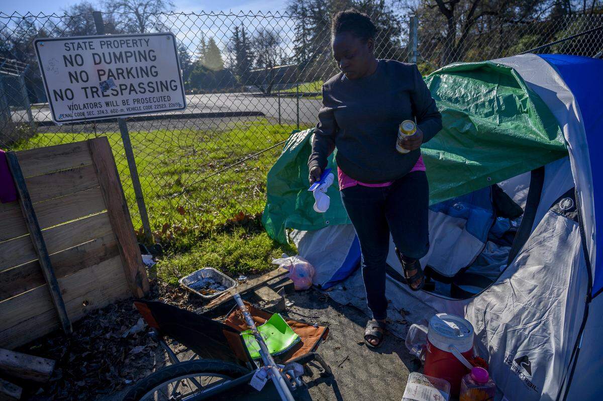 Loretta Evans, 36, says she likes living among friends who keep an eye on each other while camping on X Street in Sacramento on Thursday, Jan. 2, 2020. She is one of 394 people who spent time at the Railroad Drive shelter but never got housing. Behind her is a recently paved lot where the city plans to open a 100-bed homeless shelter in May on land owned by Caltrans.